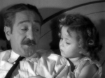 Adolphe Menjou is becoming captivated by Little Miss Marker.
